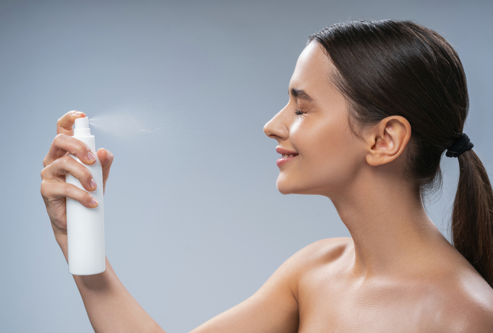 Woman spraying mist on her face.