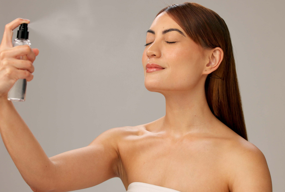 Woman using facial mist spray, eyes closed.